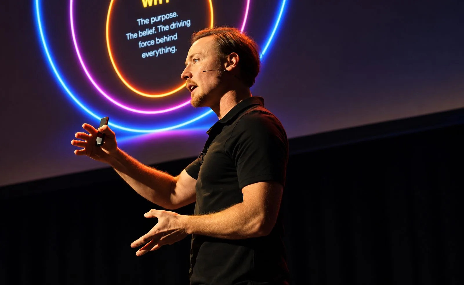 Brad Hook delivering a FLAME keynote in front of glowing neon rings