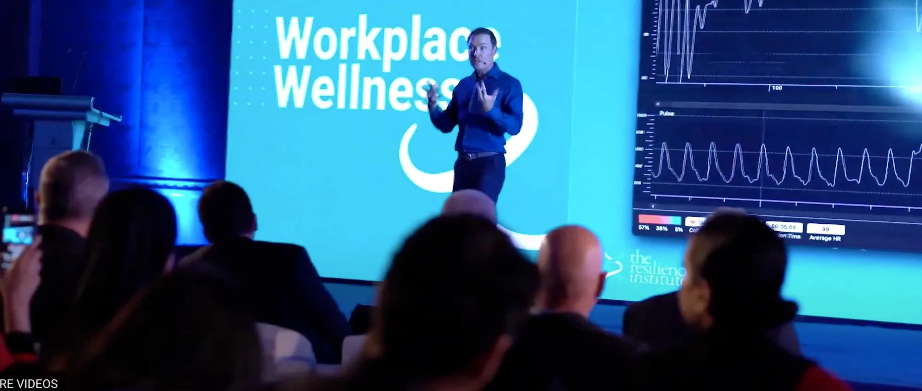Bradley Hook delivering a keynote, with a live biometrics dashboard on screen